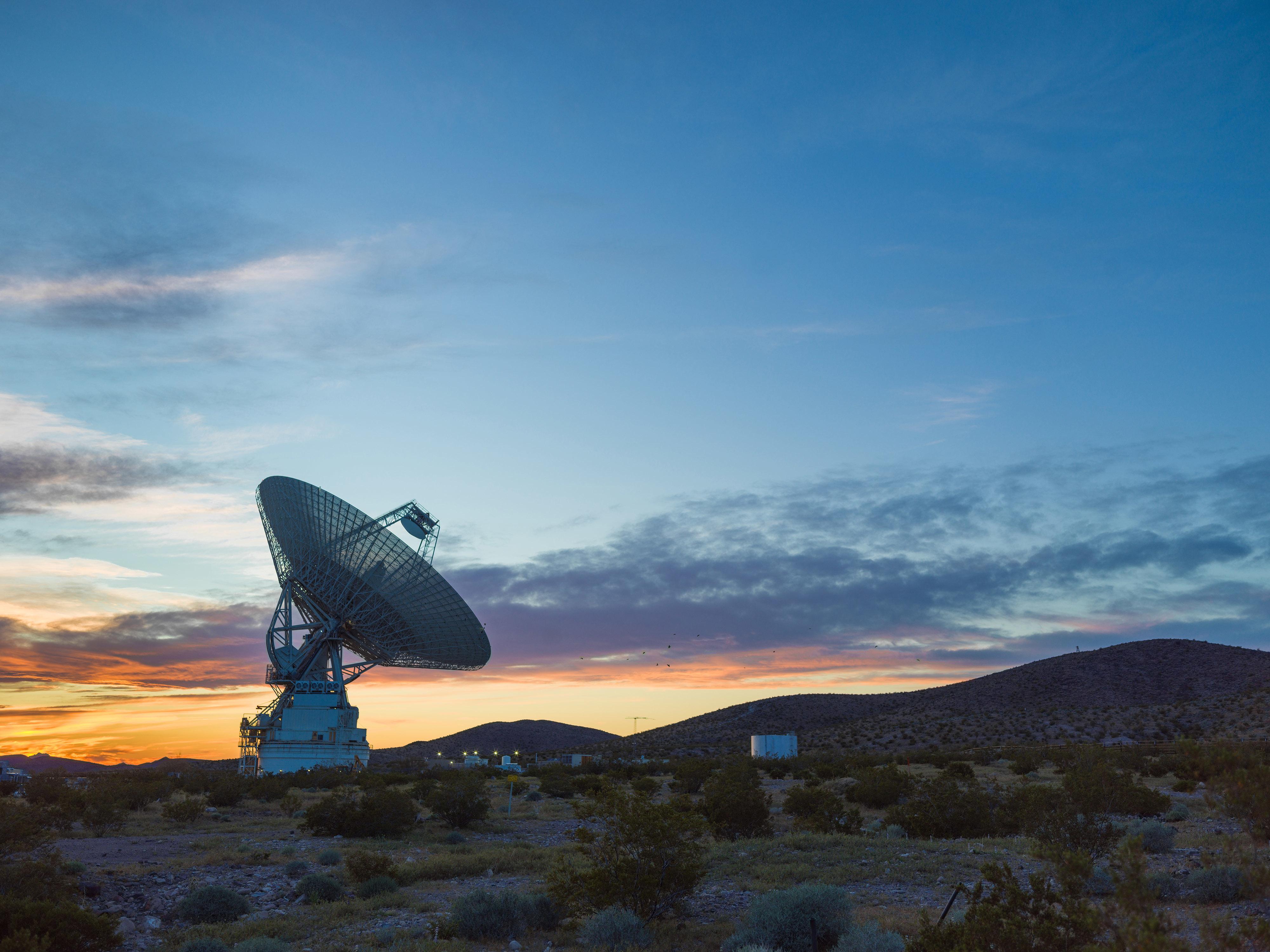 A large communications antenna silhouetted against the sunset at Goldstone